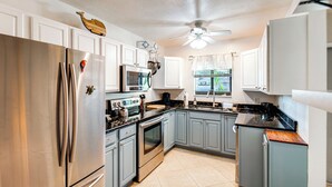 A modern kitchen with stainless steel appliances, grey cabinets, and a ceiling fan. - Relaxing Fort Myers Home w/ Screened-in Patio (Fort Myers)