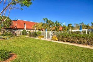 A residential property with a red-roofed house, a white fence, and a well-maintained lawn. - Relaxing Fort Myers Home w/ Screened-in Patio (Fort Myers)