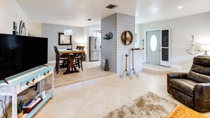 A modern living room with a flat-screen TV, a dining area, and a leather sofa. - Relaxing Fort Myers Home w/ Screened-in Patio (Fort Myers)
