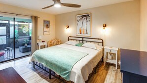 A bedroom with a bed, a ceiling fan, a nightstand, a lamp, and a view of the outside. - Relaxing Fort Myers Home w/ Screened-in Patio (Fort Myers)