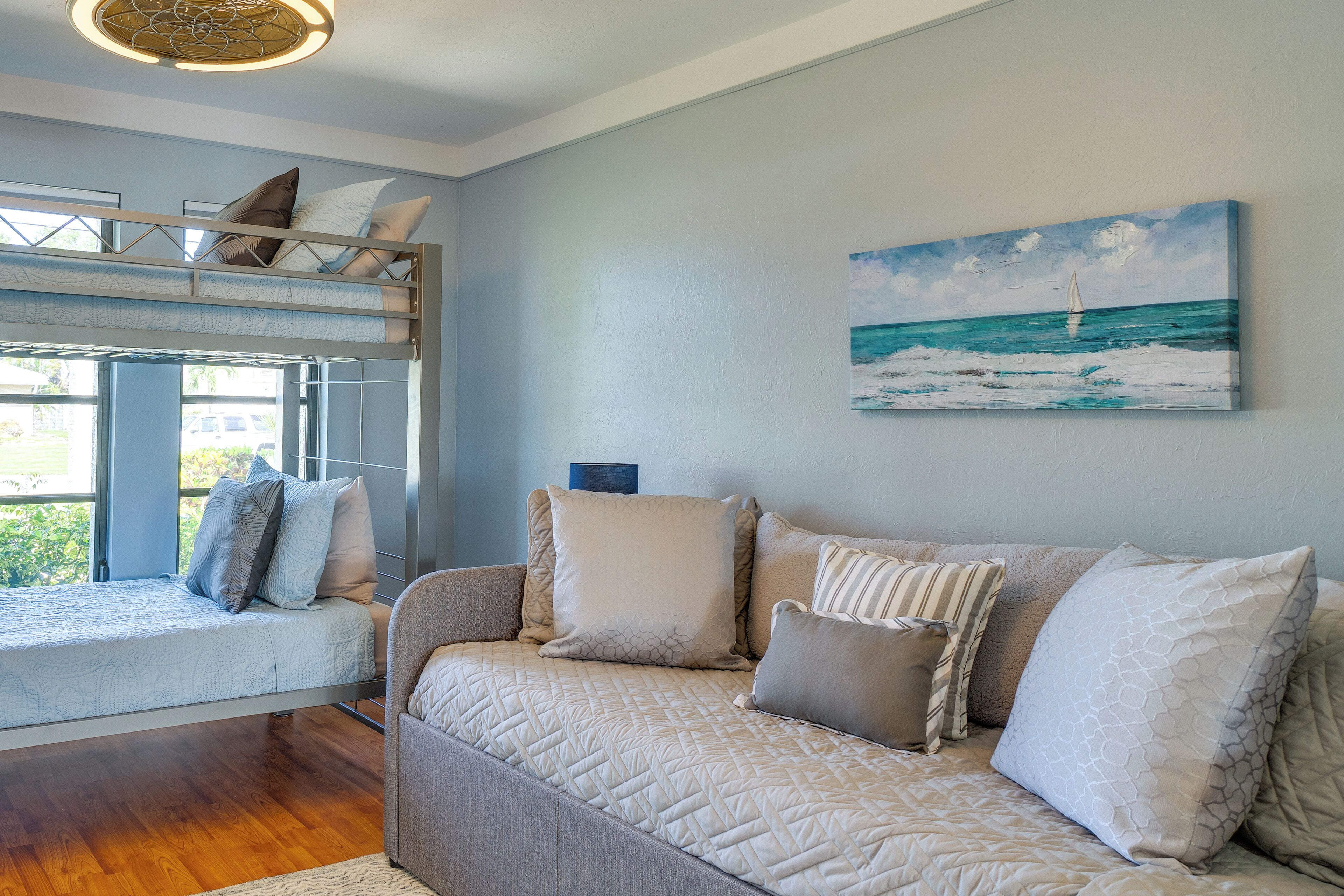Una habitación con una litera, un sofá y un cuadro de un velero en la pared.
