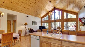 A wooden interior with a kitchen island, dining area, and a television.