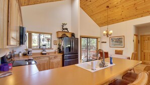 A kitchen with wooden cabinets, a refrigerator, a coffee maker, and a dining area with chairs and a table.