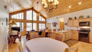 A spacious kitchen with wooden cabinets, a large island, and a dining area with a round table and chairs.