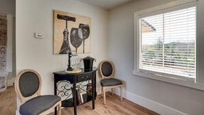 Ein Zimmer mit Holzboden, einem Schwarz-Weiß-Gemälde, einem Fenster mit Jalousien und zwei Stühlen.
