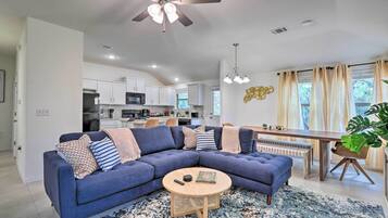 A modern living room with a sectional sofa, a round coffee table, and a dining area with a wooden table and chairs.