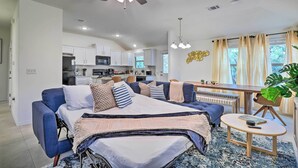 A modern living room with a sofa, a coffee table, and a dining area. - Modern Granite Shoals Retreat w/ Fire Pit! (Marble Falls)