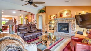 A living room with leather sofas, a glass coffee table, a fireplace, and a television. - Rustic Tucson Vacation Rental w/ Pool & Spa! (Saddlebrooke)