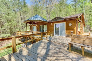 Une cabane en bois dotée d’une terrasse, de grandes fenêtres et d’un patio couvert.