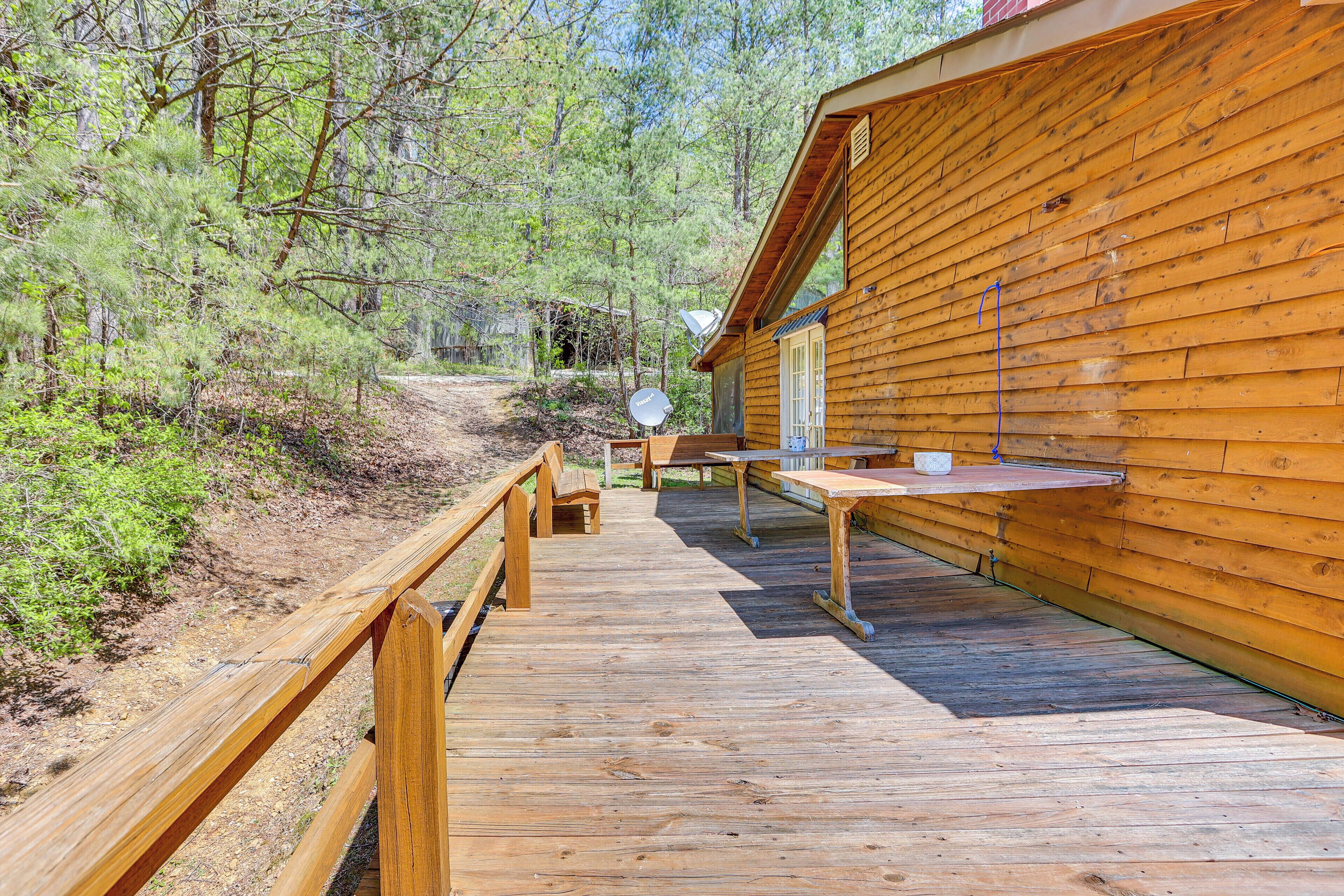 A wooden deck leading to a cabin with satellite dishes, surrounded by forest.