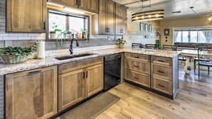 A modern kitchen with wooden cabinets, granite countertops, and a built-in dishwasher. - Hot Tub & Deck: Pet-friendly Home in Payson (Payson)