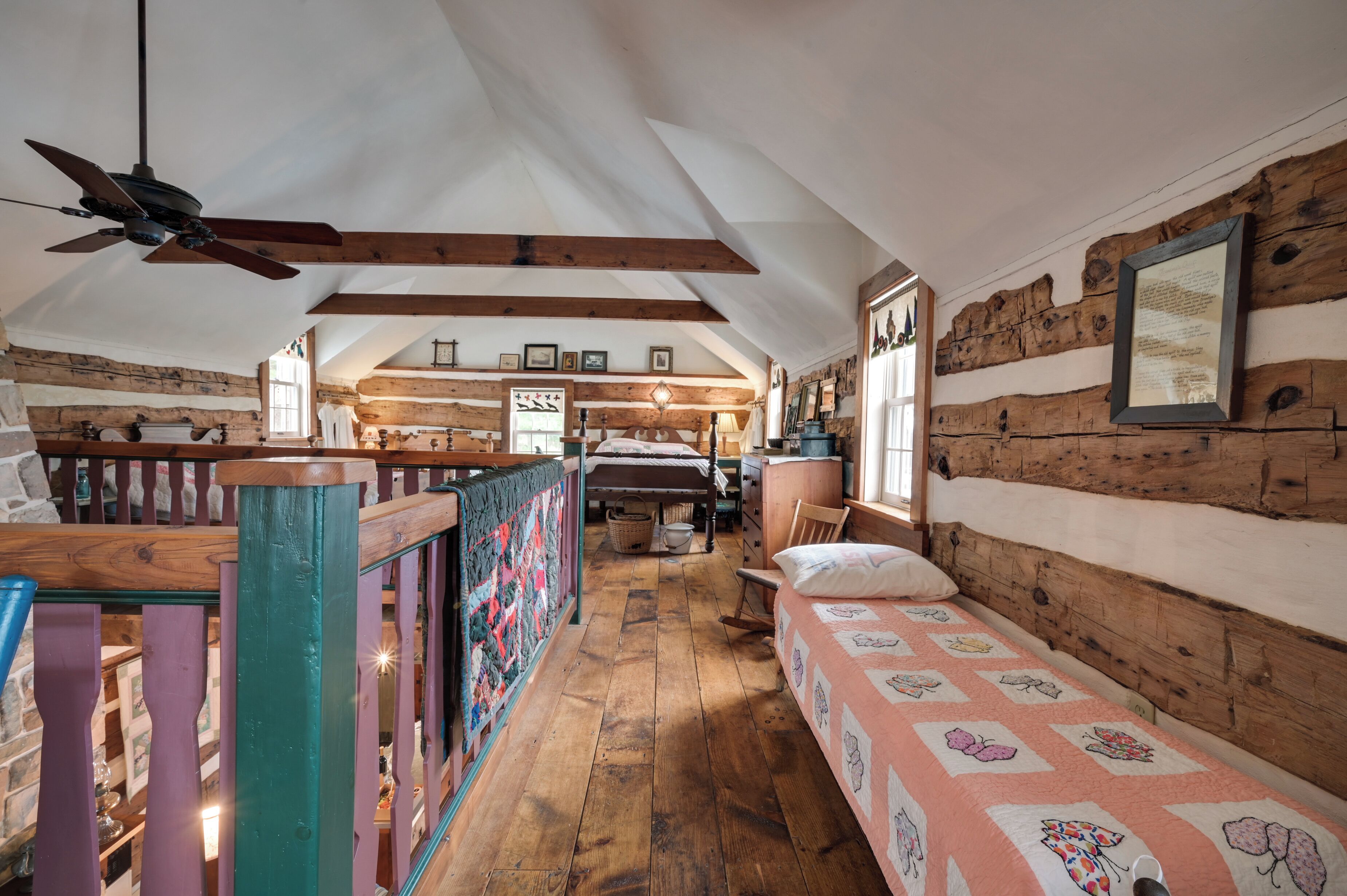 A cozy attic bedroom with wooden beams, a sloped ceiling, and a bed with a floral quilt.
