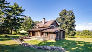 A log cabin with a porch, stone wall, and a view of the surrounding forest. - Cabin Vacation Rental ~ 8 Mi to Penn State! (Pennsylvania Furnace)