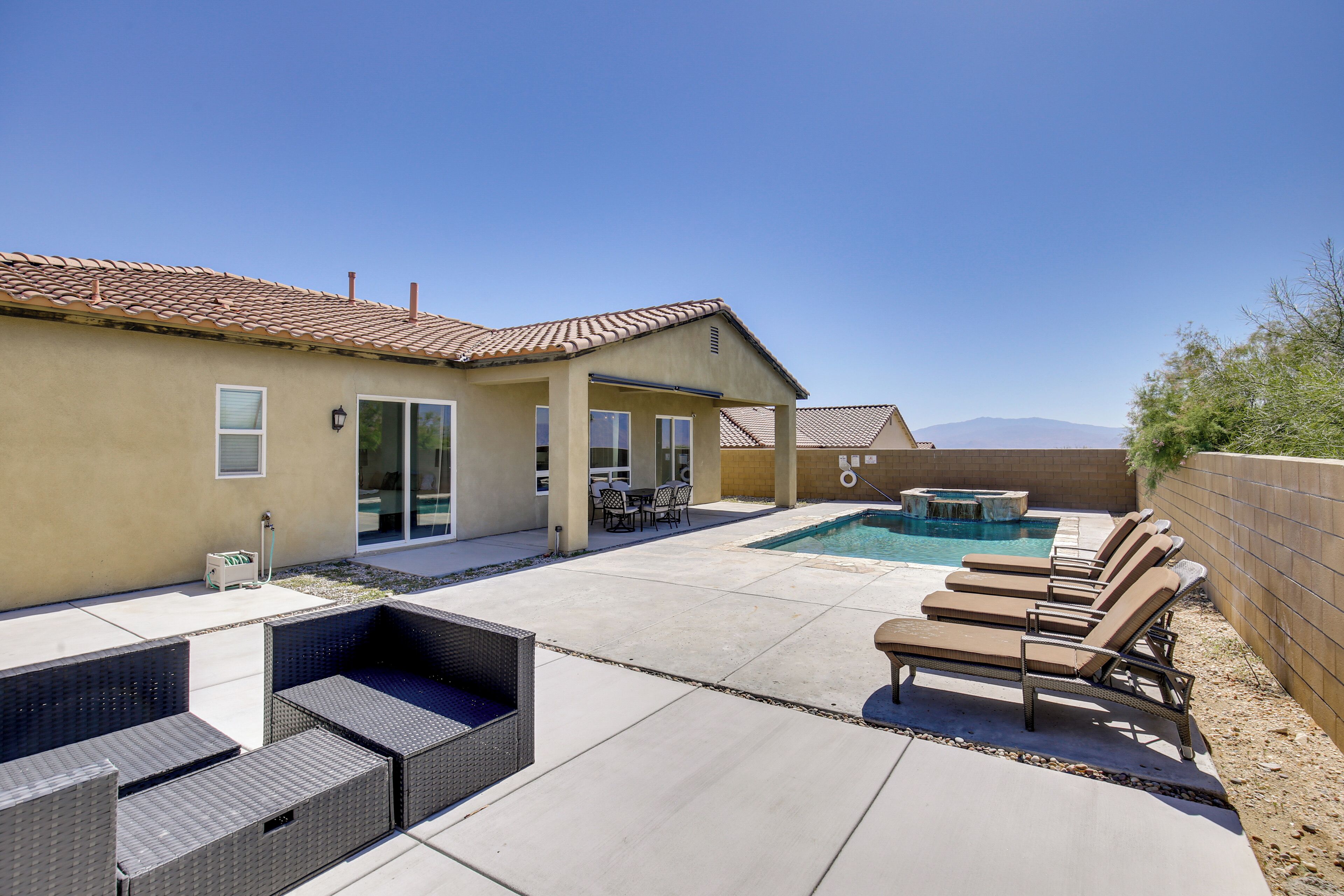 Un jardin avec une piscine, des chaises longues et un espace patio.
