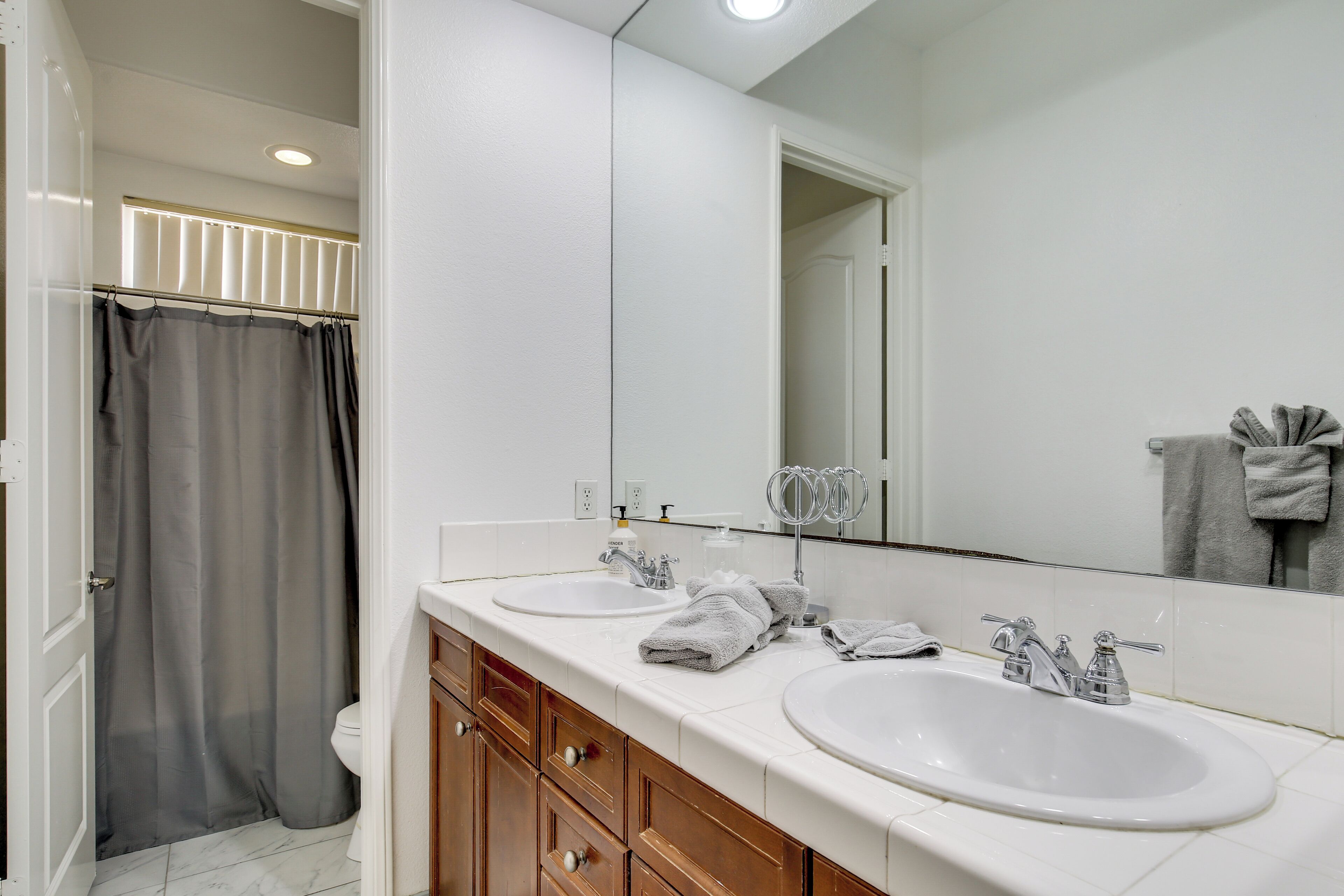 A bathroom with two sinks, a mirror, and a shower curtain.