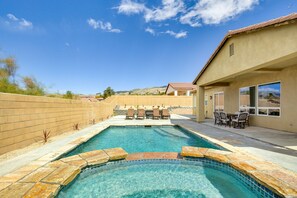 Relax by the pool surrounded by a patio with a table and chairs.