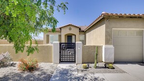 A residential house with a gated entrance, a garage, and a small garden with cacti and a flowering plant. - 'casa Del Sol' - Cozy Oasis in Desert Hot Springs! (Desert Hot Springs)