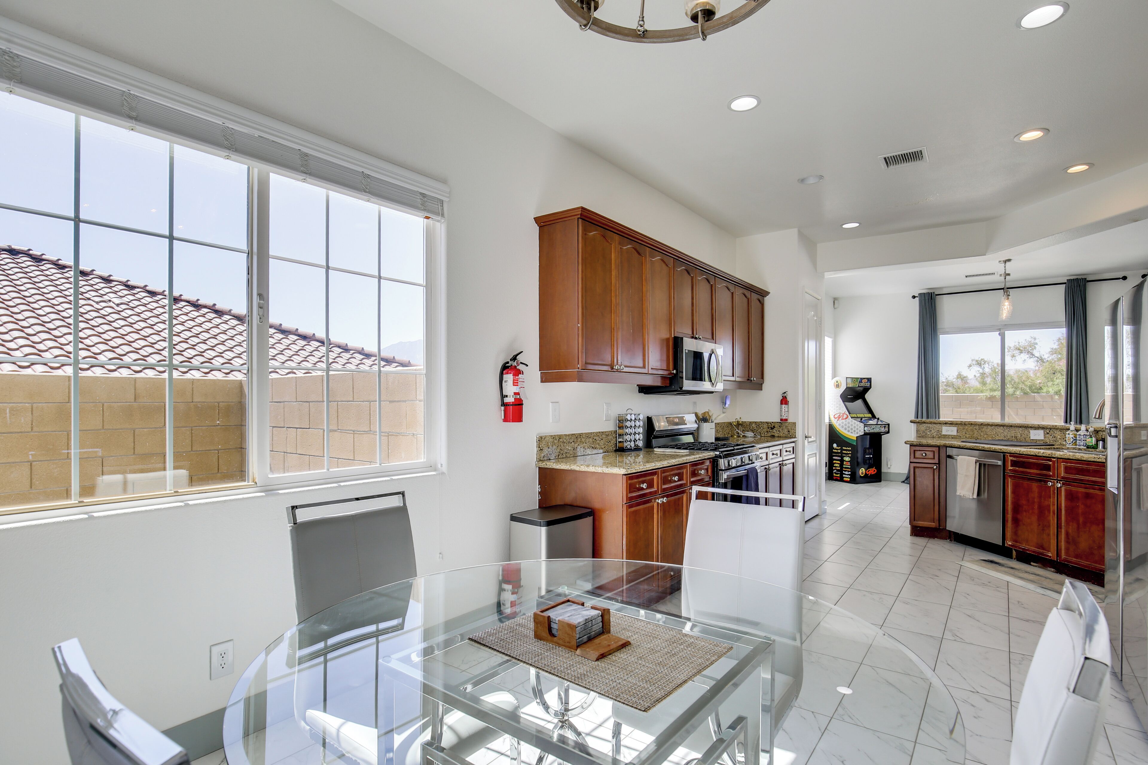 A modern kitchen with wooden cabinets, a glass dining table, and a large window.