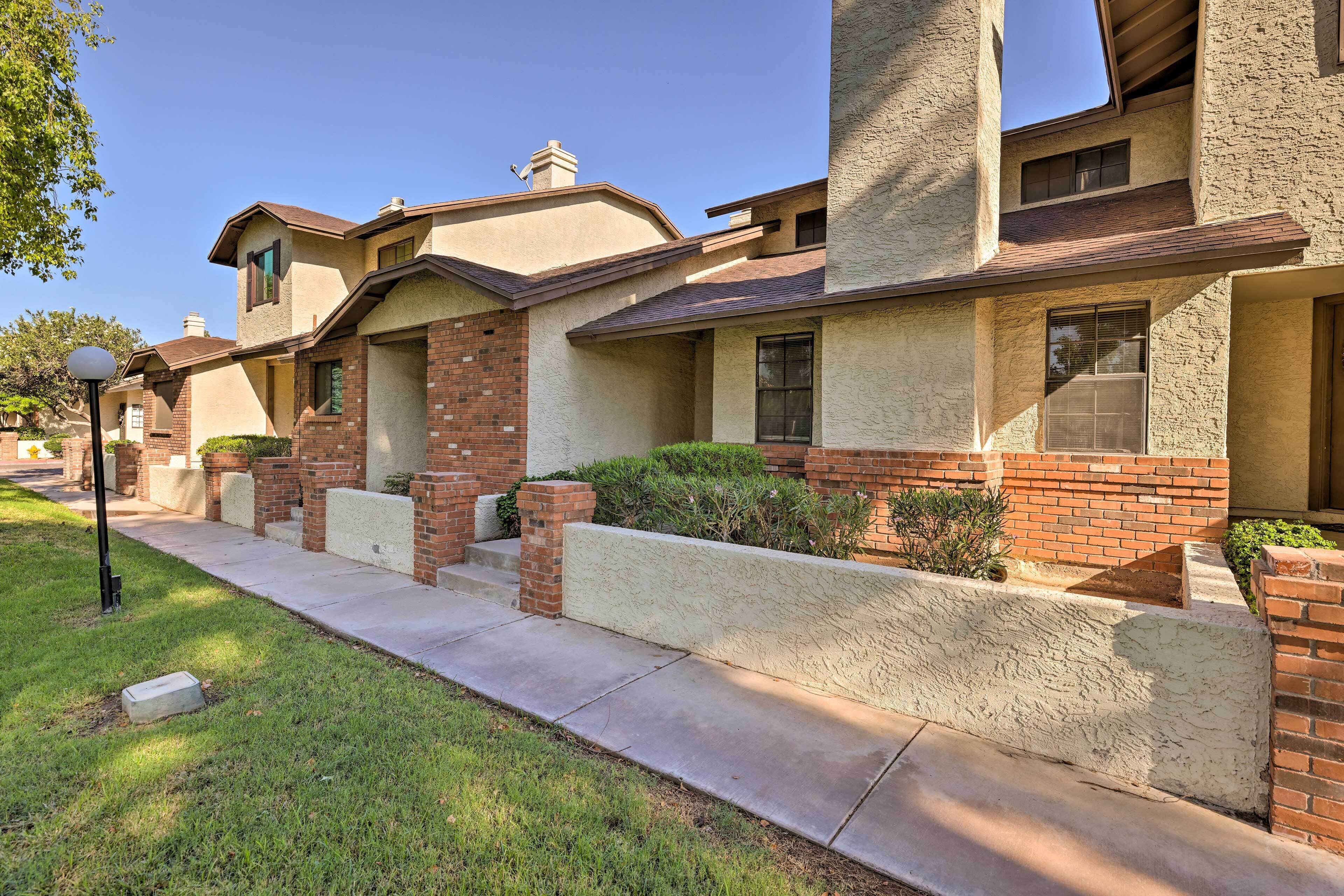 A row of townhouses with brick and stucco exteriors, a concrete sidewalk, and a street lamp.