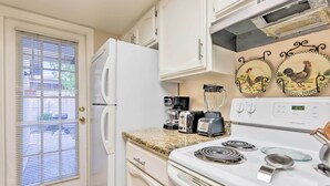 A kitchen with white cabinets, a white refrigerator, a stove, a coffee maker, and two wall-mounted clocks. - Gilbert Townhome w/ Easy Access to Phoenix! (Gilbert)