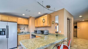 A kitchen with granite countertops, stainless steel appliances, wooden cabinets, and a bar area with red chairs. - Paradise Valley Cottage Near Hiking Trails! (Paradise Valley)