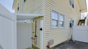 A house with a covered porch, a small front yard, and a white fence. - Brigantine Condo w/ Gas Grill - Walk to Beach! (Brigantine)
