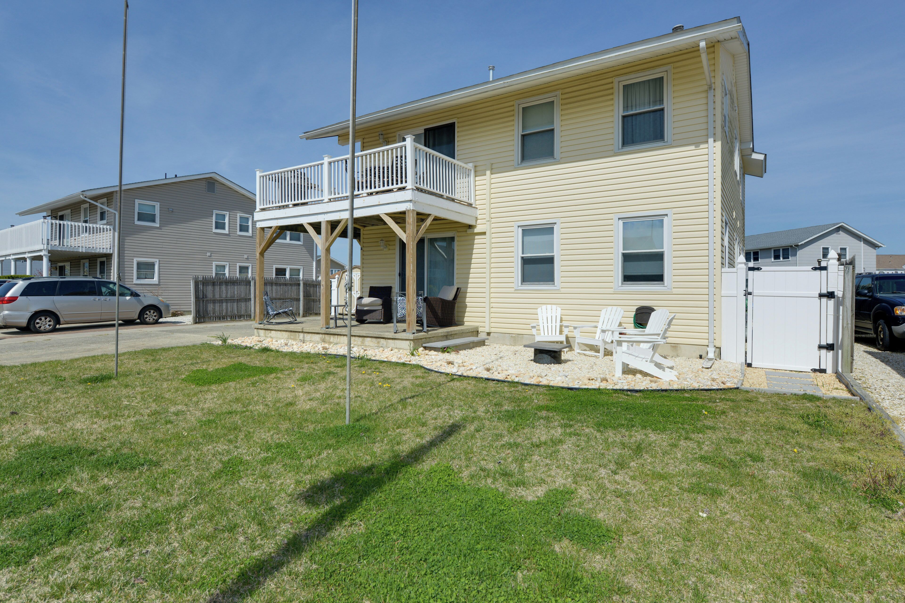 A two-story house with a balcony, a fenced yard, and a parked car.