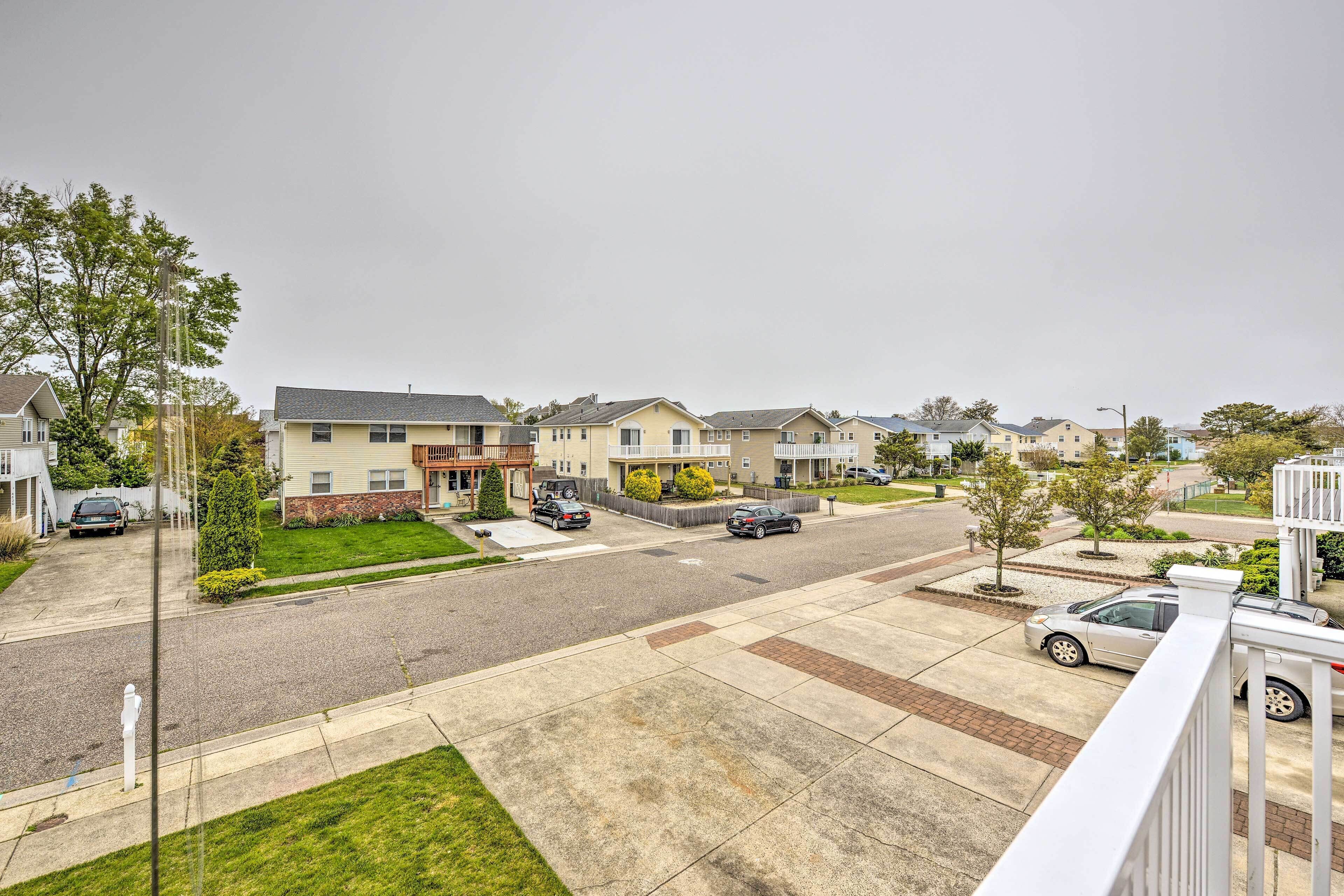 A residential street with houses, cars, and a sidewalk.