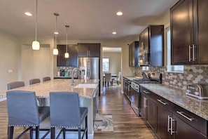 A modern kitchen with granite countertops, dark cabinetry, and stainless steel appliances.