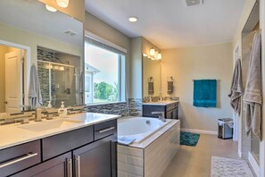 A modern bathroom with two sinks, a large bathtub, and a walk-in shower.