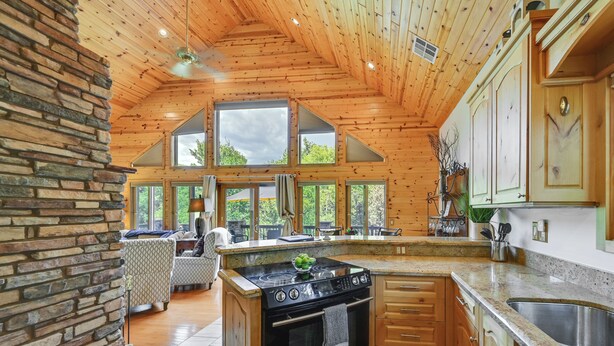A spacious kitchen with a large island, wooden cabinets, and a stone accent wall. - Log Cabin in Payson w/ Deck, Mtn & Creek Views (Payson)