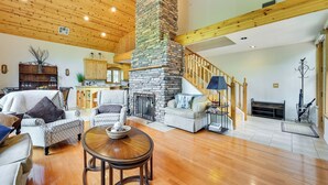 A spacious living room with wooden floors, a stone fireplace, and a staircase leading to an upper level. - Log Cabin in Payson w/ Deck, Mtn & Creek Views (Payson)