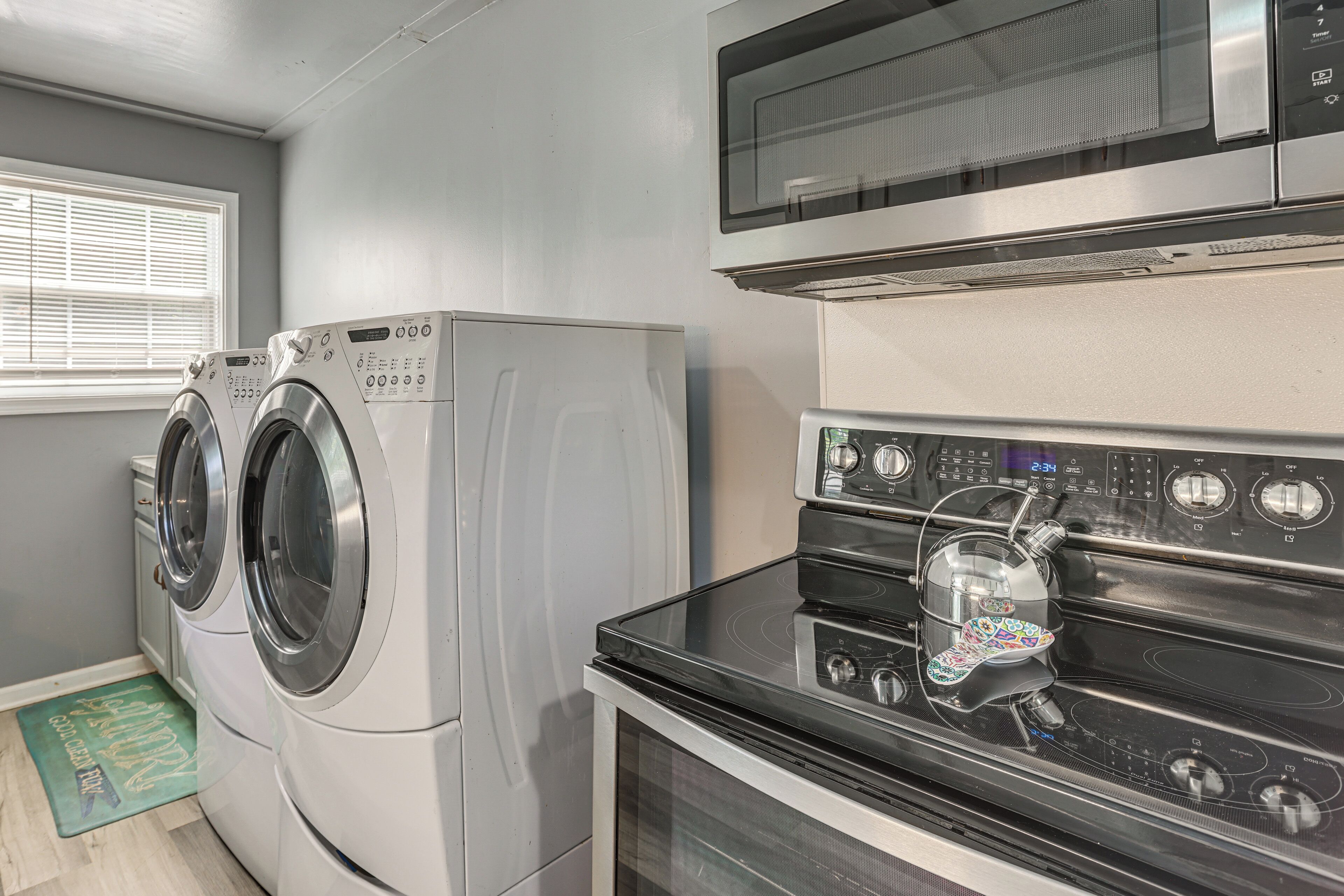 A laundry area with two front-loading washers, a microwave, and a stove.