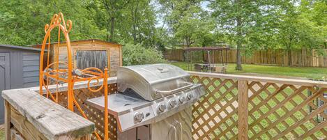 Un jardin avec un barbecue, une terrasse en bois et une clôture en bois.