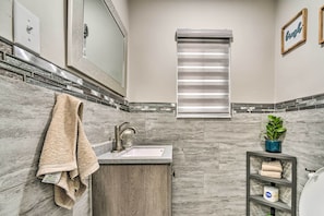 A bathroom with a sink, towel rack, and a shelf with toiletries.