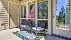 Une terrasse couverte avec deux fauteuils en osier et un tapis aux couleurs vives.