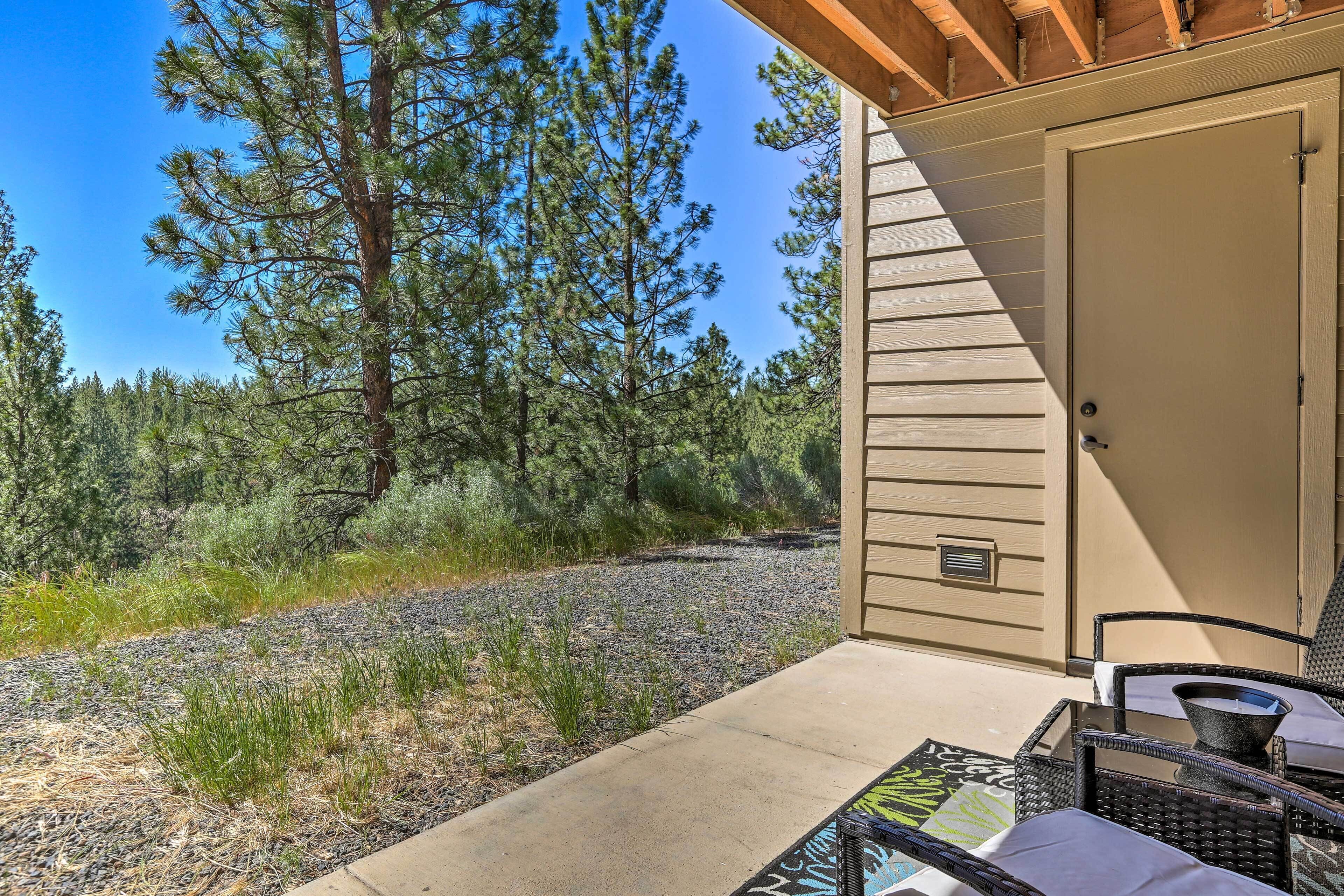 A patio area with outdoor furniture, a door, and a view of a forest.
