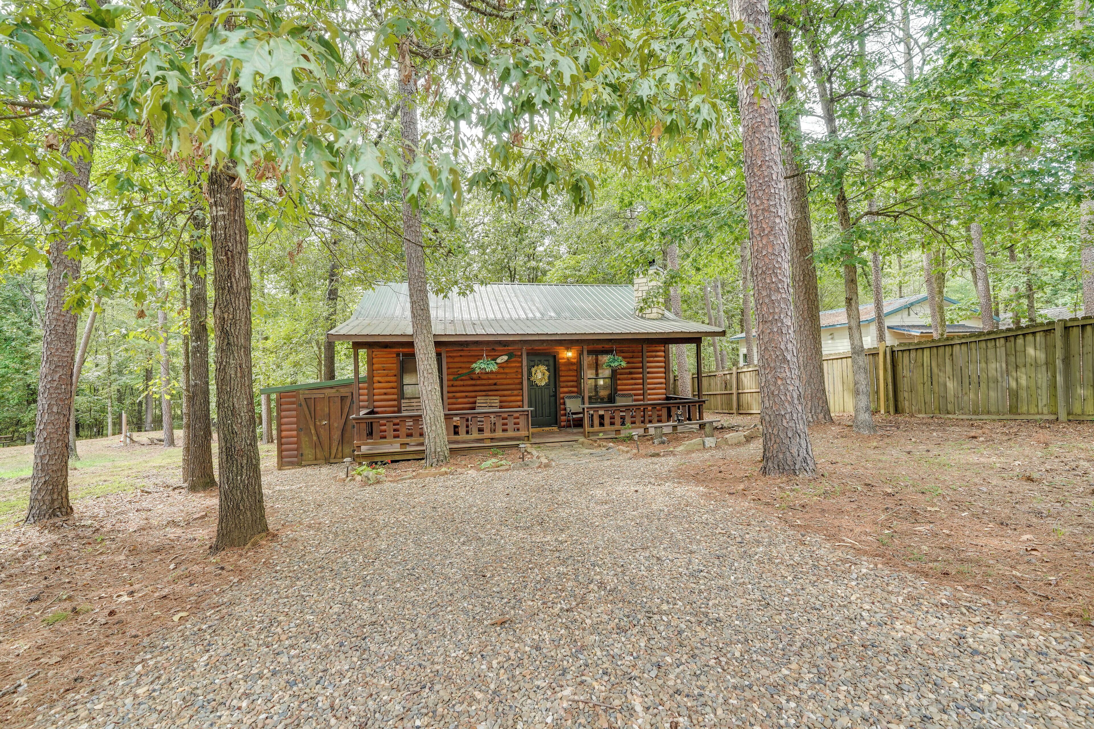 A rustic cabin with a wooden exterior, a porch with benches, and a gravel ground.