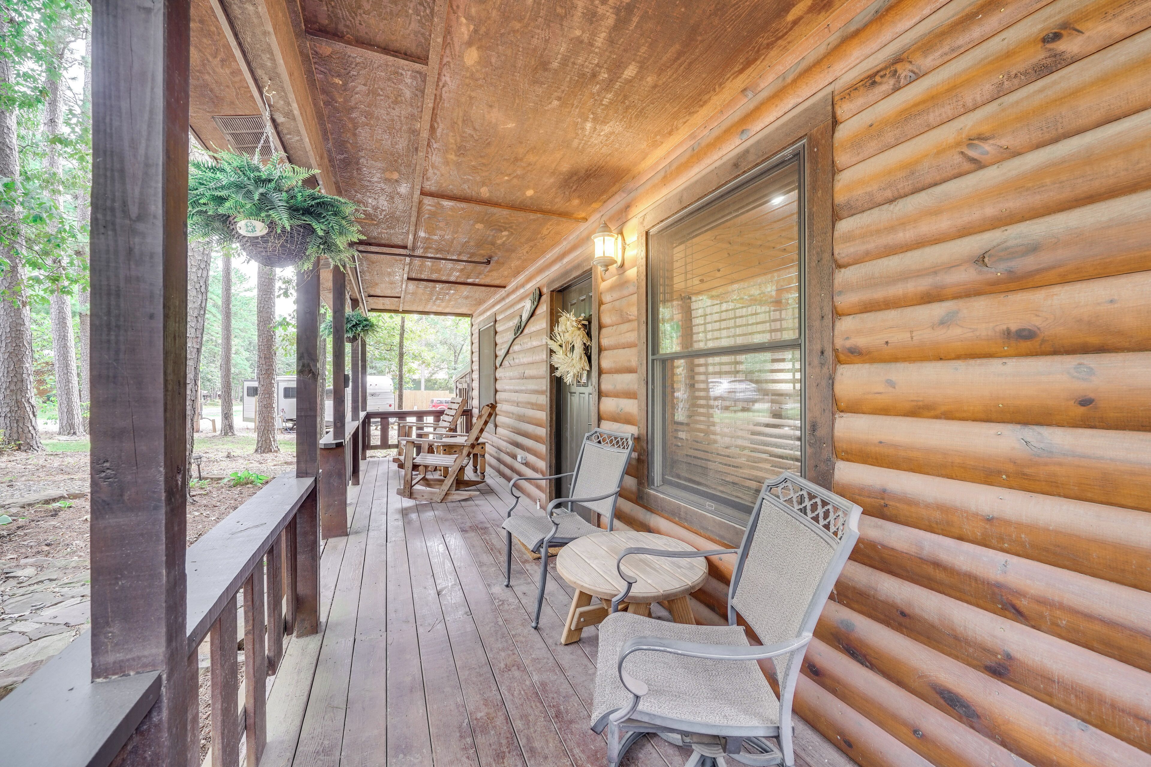 A wooden cabin with a porch, outdoor seating, and hanging plants.