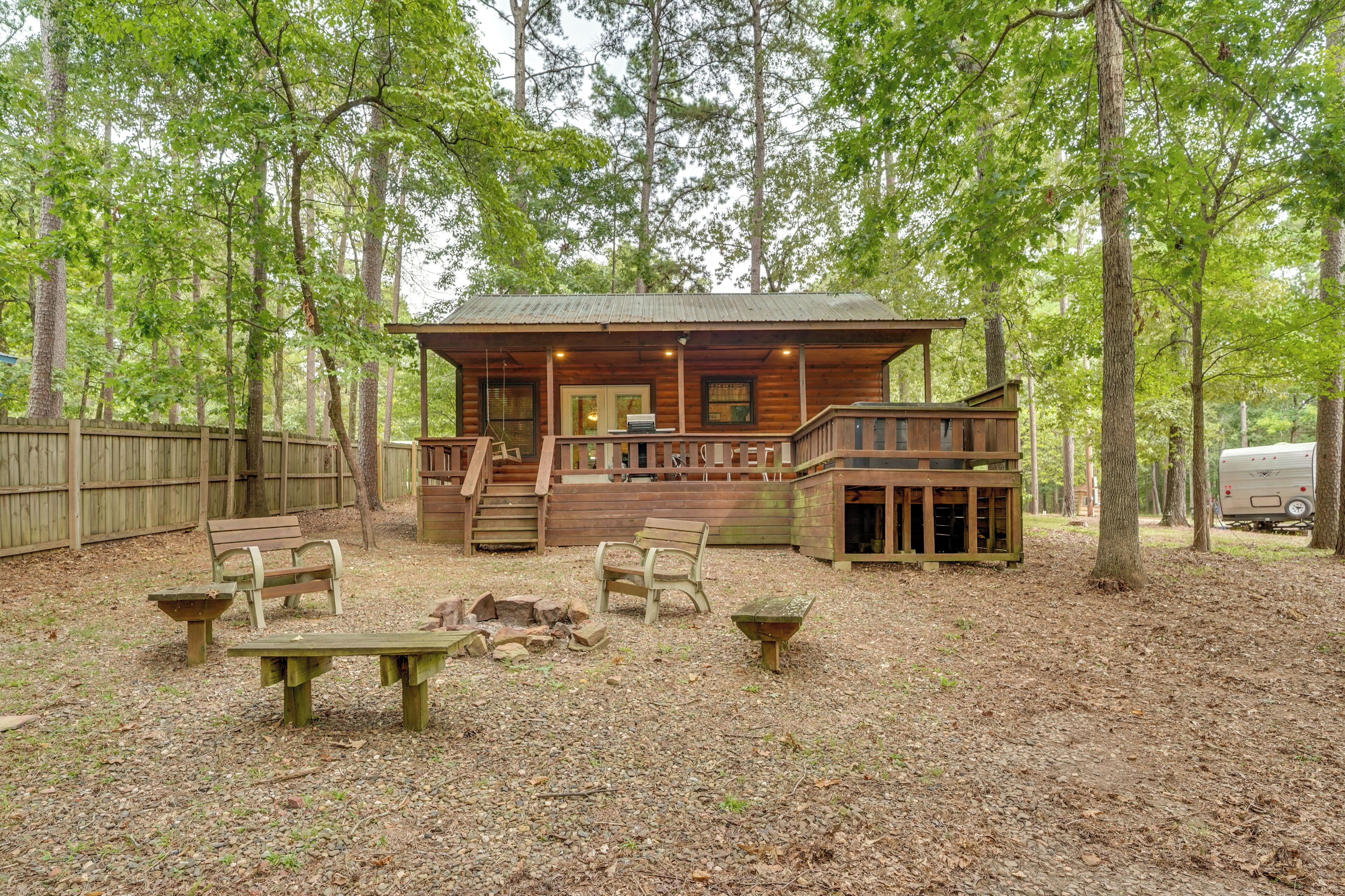 Un chalet rustique doté d’une véranda, de bancs en bois et d’une table de pique-nique, situé dans un espace boisé.