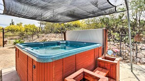 A hot tub with a wooden exterior and a metal frame, surrounded by a shaded area and a wooden bench. - Lovely Tucson Home w/ Private Pool & Hot Tub! (Tucson)