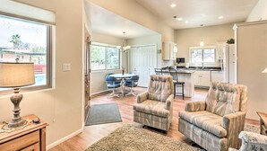 A spacious living room with a large window, a dining area, and a kitchen. - Lovely Tucson Home w/ Private Pool & Hot Tub! (Tucson)