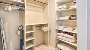 A walk-in closet with shelves for folded clothes, a hanging rod for garments, and a vacuum cleaner. - Lovely Tucson Home w/ Private Pool & Hot Tub! (Tucson)