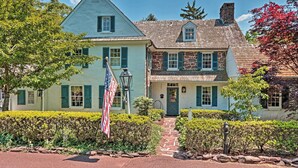 Une maison à deux étages avec une cheminée en pierre, un porche à l’avant et un drapeau.