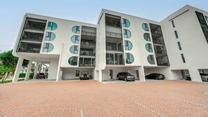 Un bâtiment moderne à plusieurs étages, doté d’un toit plat, de grandes fenêtres et d’une cour pavée.