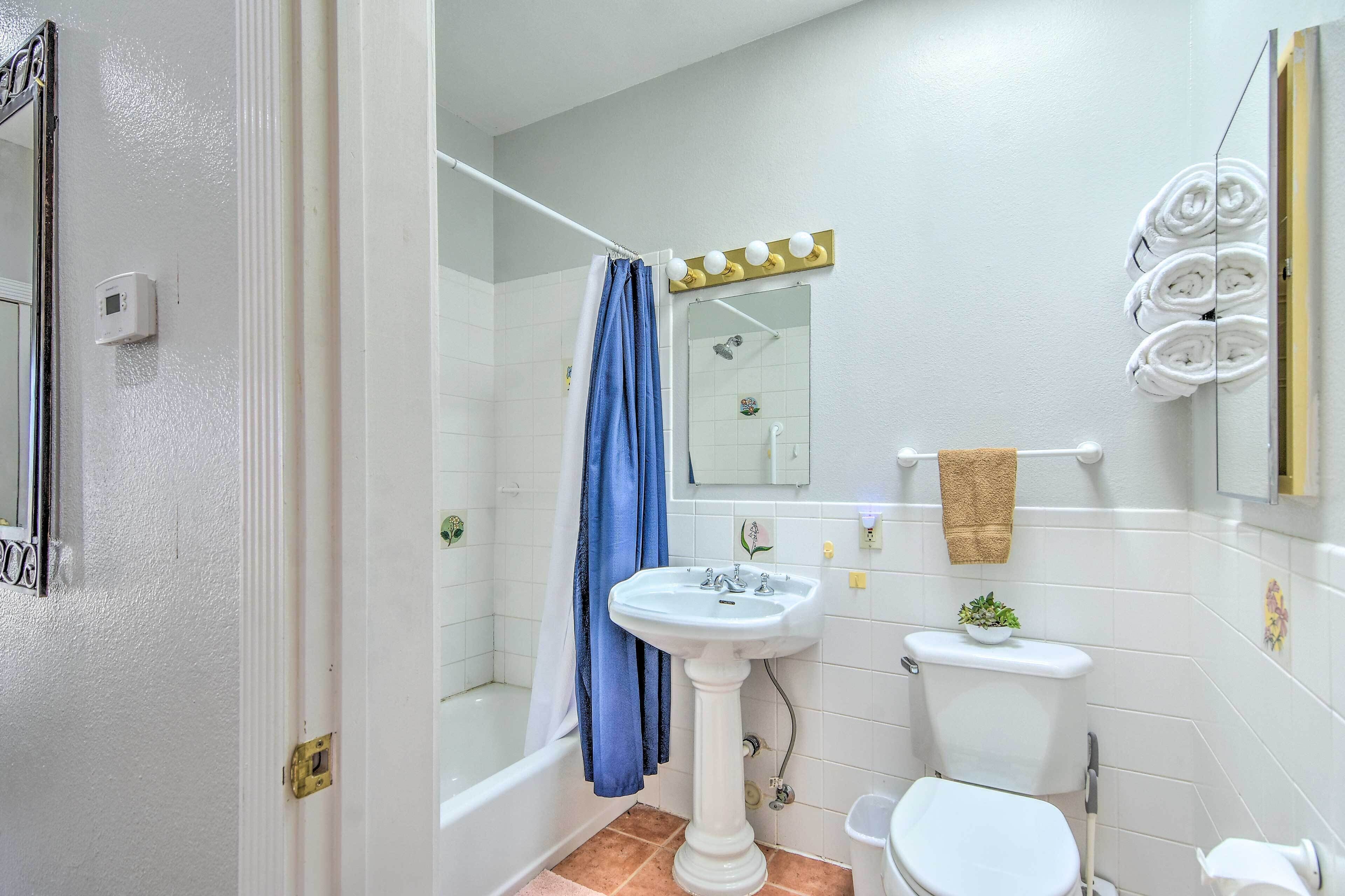 Een badkamer met een bad, wastafel, toilet en douchegordijn.