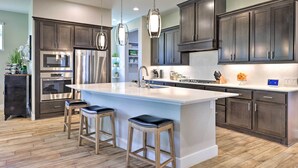 A modern kitchen with dark cabinets, stainless steel appliances, and a central island with stools. - Upscale Austin Area Escape: Families Welcome! (Austin)