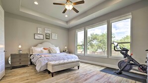 A bedroom with a bed, a desk, a standing fan, and a stationary bike. - Upscale Austin Area Escape: Families Welcome! (Austin)