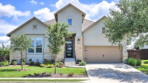 A two-story house with a garage, a front porch, and a well-maintained lawn. - Upscale Austin Area Escape: Families Welcome! (Austin)