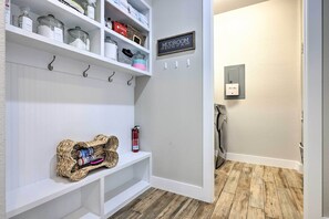 A hallway with a white bench, shelves with storage containers, a fire extinguisher, and a sign that reads "MUDROOM". - Upscale Austin Area Escape: Families Welcome! (Austin)